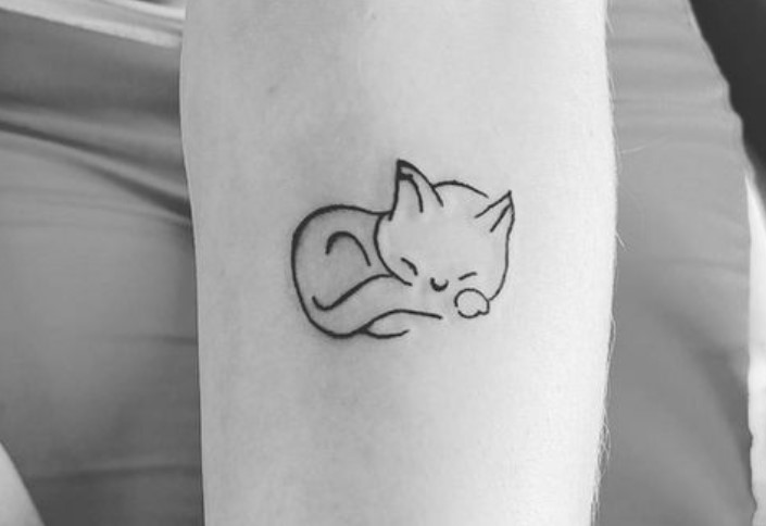 outline of a sleeping cat tattoo on the forearm
