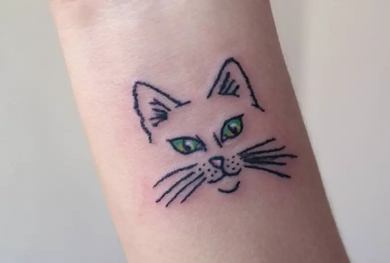 face of a cat with green eyes tattoo on the wrist