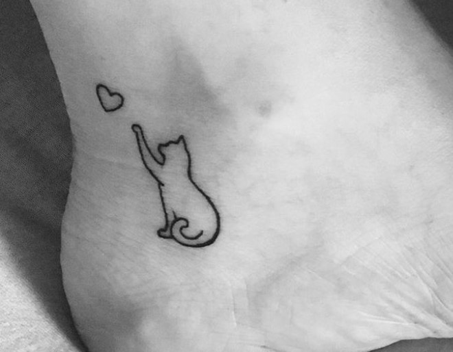 outline of a cat grabbing a heart tattoo on the heel