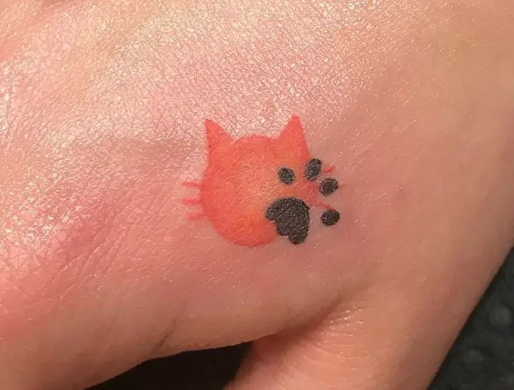 orange cat shape and black paw tattoo on the hand
