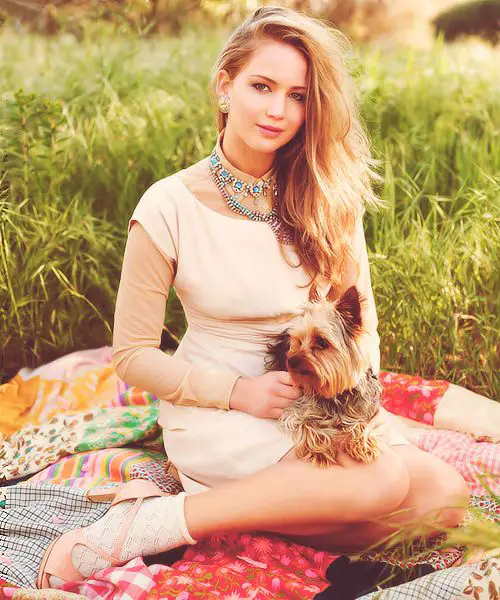 Jennifer Lawrence sitting on a blanket in the field with her Yorkshire Terrier in her lap