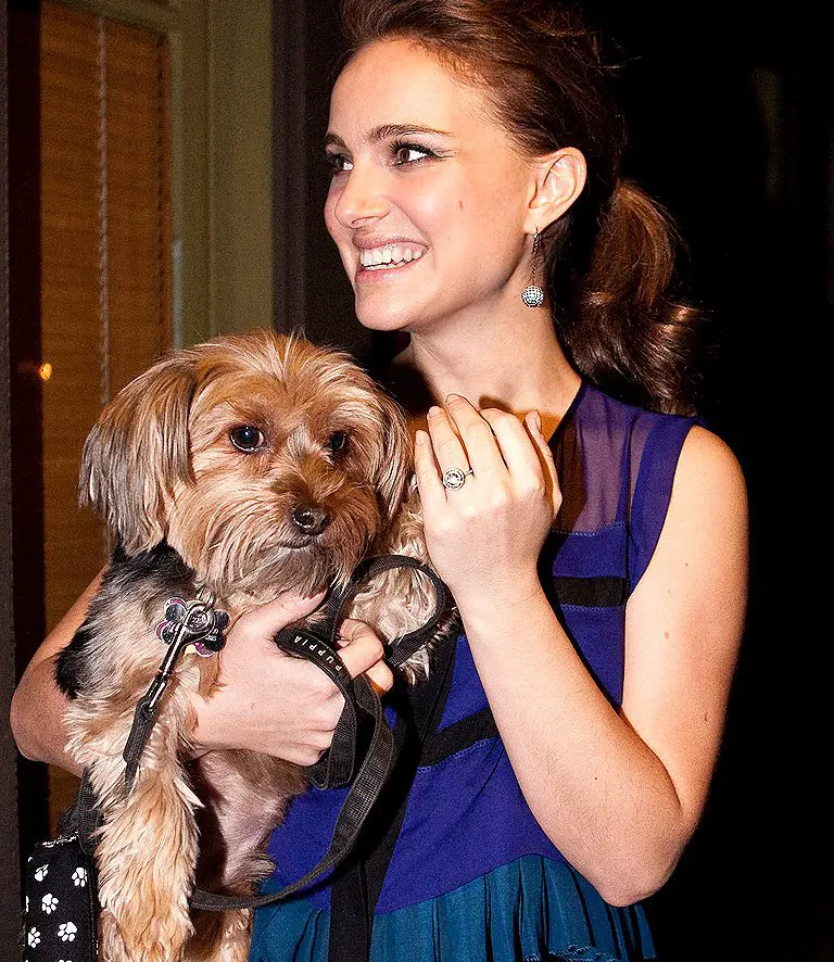 Natalie Portman looking sideways while smiling and carrying her Yorkshire Terrier