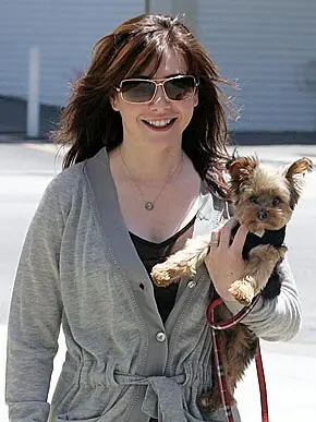 ALYSON HANNIGAN walking while holding her Yorkshire Terrier