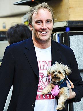 JAY MOHR waling in the street while carrying his Yorkshire Terrier
