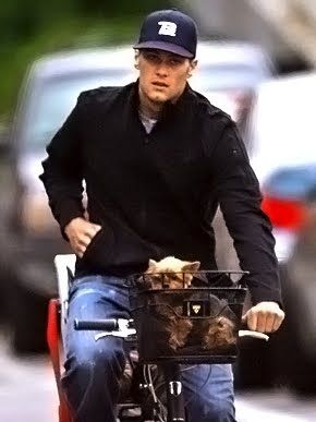 TOM BRADY riding a bicycle with his Yorkshire Terrier in a basket connected to the handlebar 