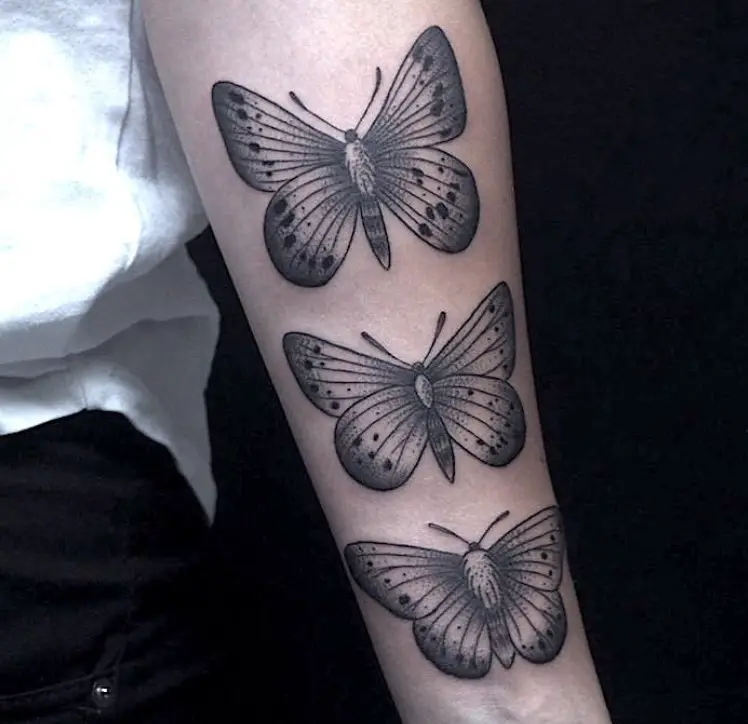 Three black butterfly tattoos on forearm