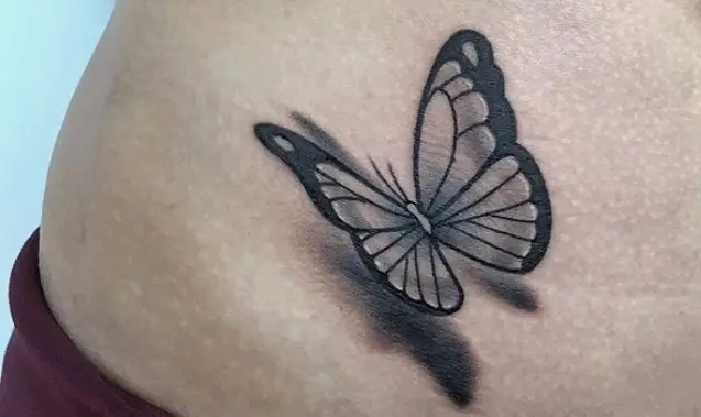 Black 3D butterfly tattoo on stomach.