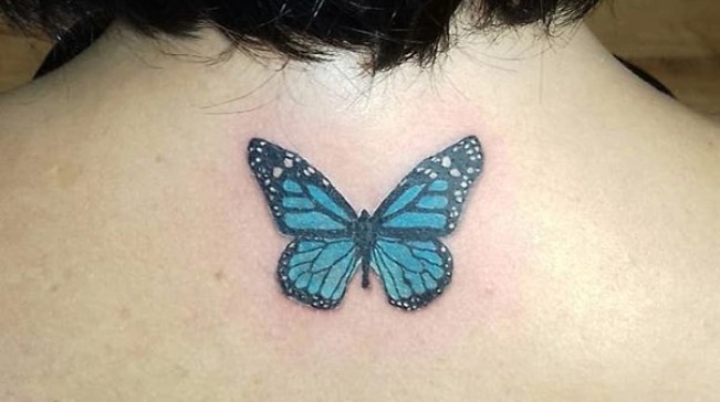 Blue butterfly tattoo on back on the back of neck.