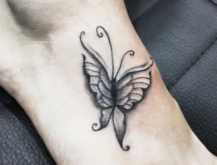 Black outline butterfly tattoo on feet.
