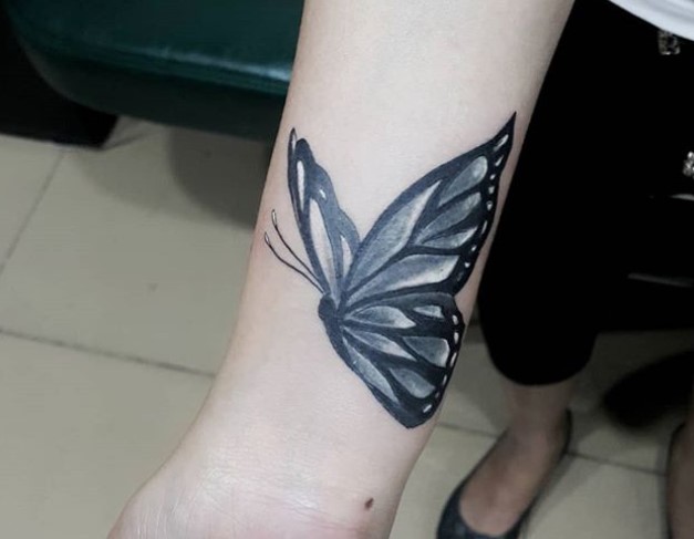Black butterfly tattoo on wrist