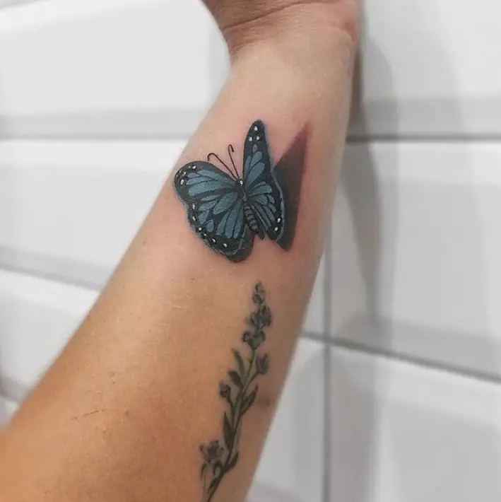 Blue 3D butterfly tattoo on forearm.