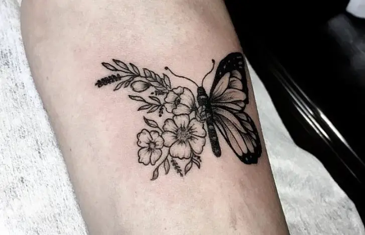 Black butterfly on flowers tattoo on legs