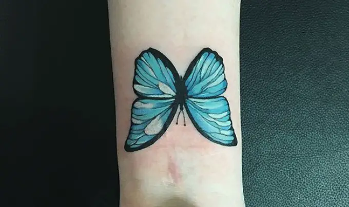 Blue green butterfly tattoo on wrist