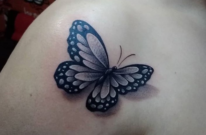 Black butterfly tattoo on shoulder
