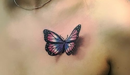 Vibrant blue and pink realistic butterfly tattoo on chest