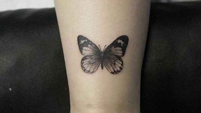 Black butterfly tattoo on leg.