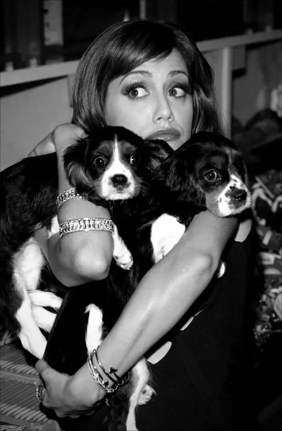 black and white photo of Brittany Murphy hugging her two Cocker Spaniel puppies