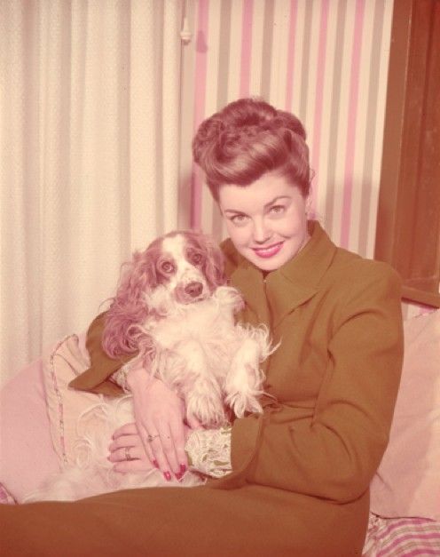 Esther Williams sitting on the couch while hugging her Cocker Spaniel beside her