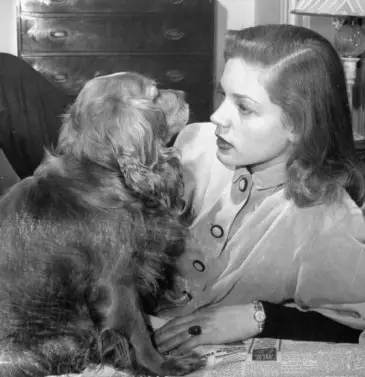 Lauren Bacall talking to her Cocker Spaniel while lying on the floor