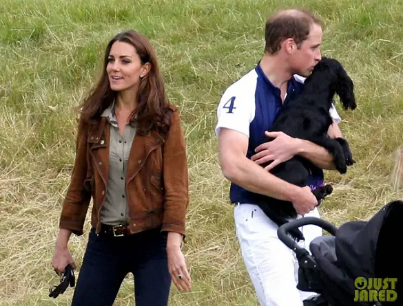 Prince William kissing his black Cocker Spaniel and Kate Middleton talking to someone