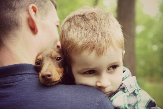 A man carrying a kid and a Dachshund