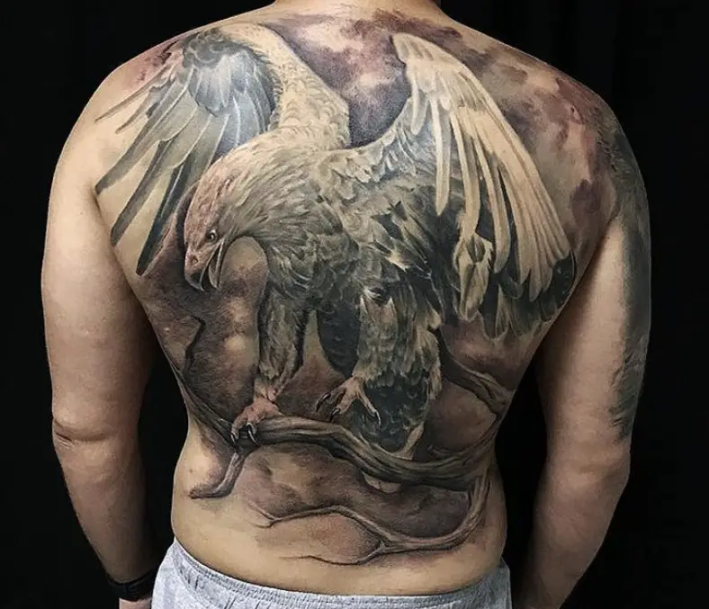 realistic Eagle landing on the branch of a tree tattoo on the back