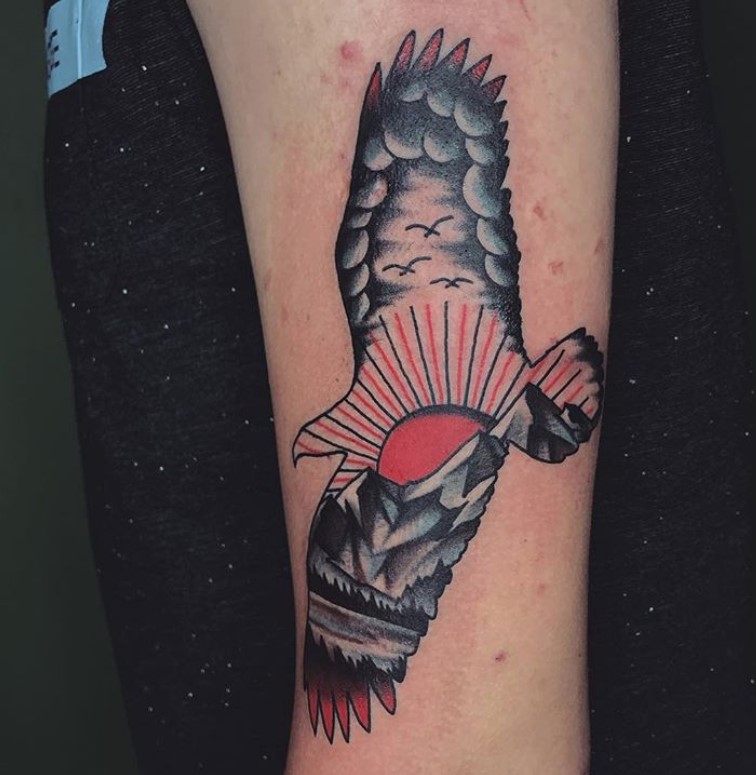 a sunset on a mountain with a flock of bird flying in the sky design on a soaring eagle tattoo.