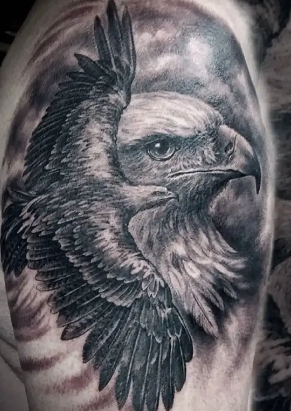 black and gray 3D tattoo on the leg of a Eagle souring in a large sideview head of an Eagle