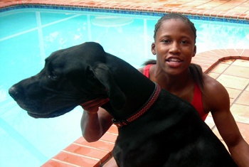 Lauryn Williams sitting by the pool with a black Great Dane in front of her