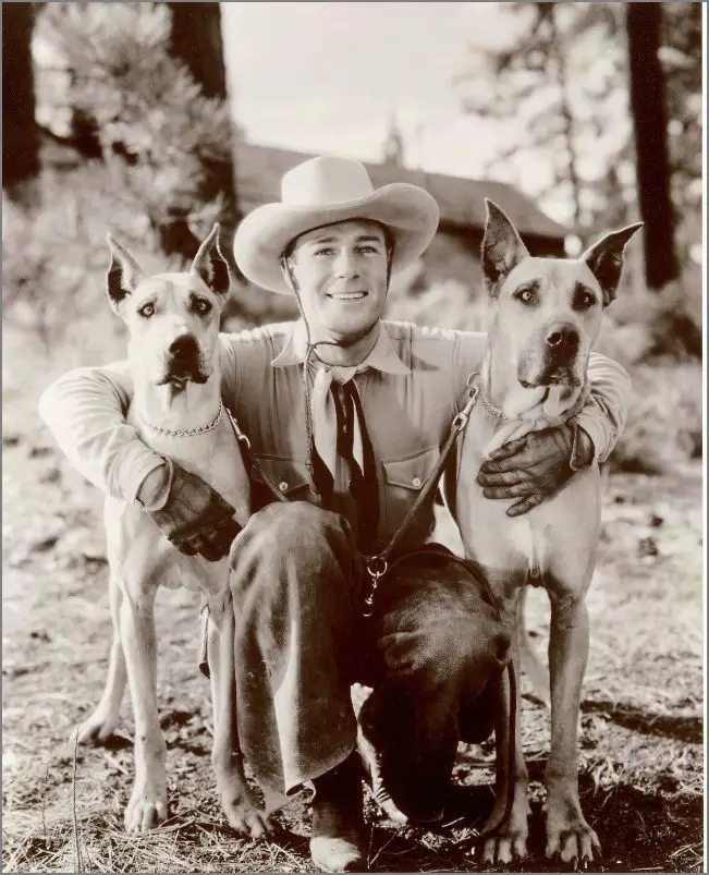 Randolf Scott with his arms around his two Great Danes standing beside him