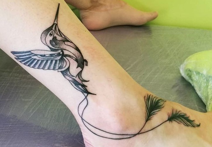 tribal humming bird tattoo on calf with its feathers going to feet