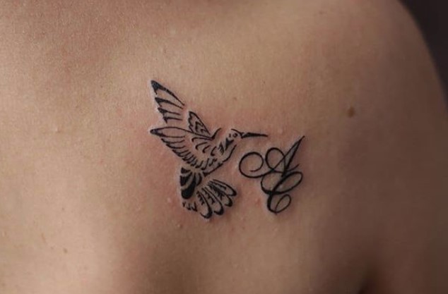 small hummingbird with initials tattoo on back