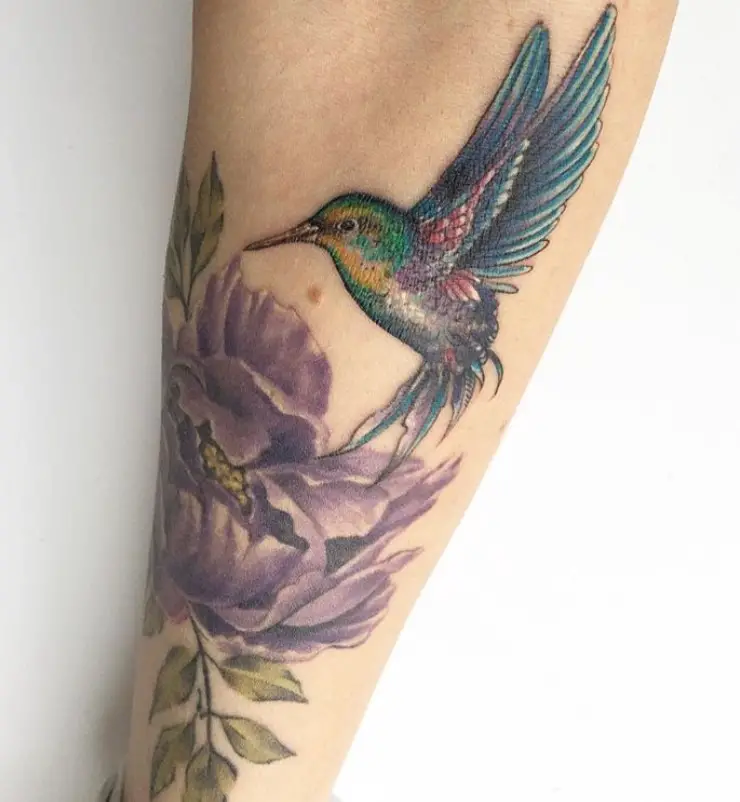colorful humming bird in purple flower tattoo on forearm