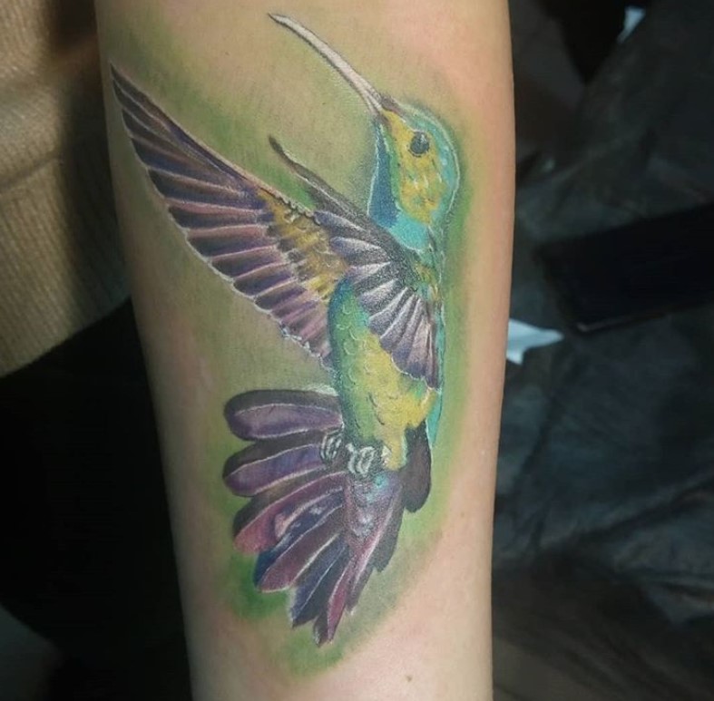 colorful hummingbird with white outline tattoo on the forearm