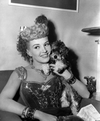 A black and white photo of Betty Grable holding her poodle.