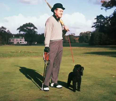 Bob Hope standing in the yard with his black poodle