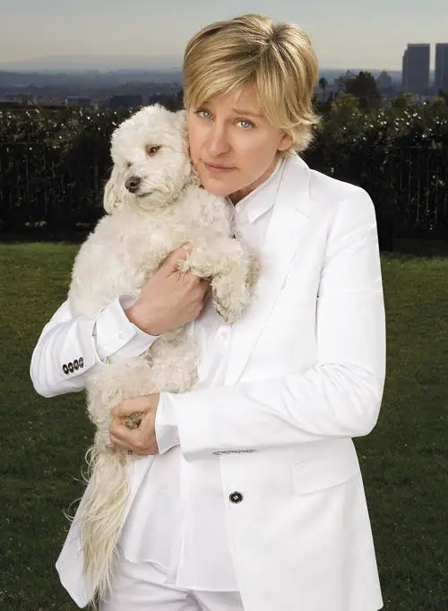 Ellen Degeneres standing in the yard while holding her white poodle