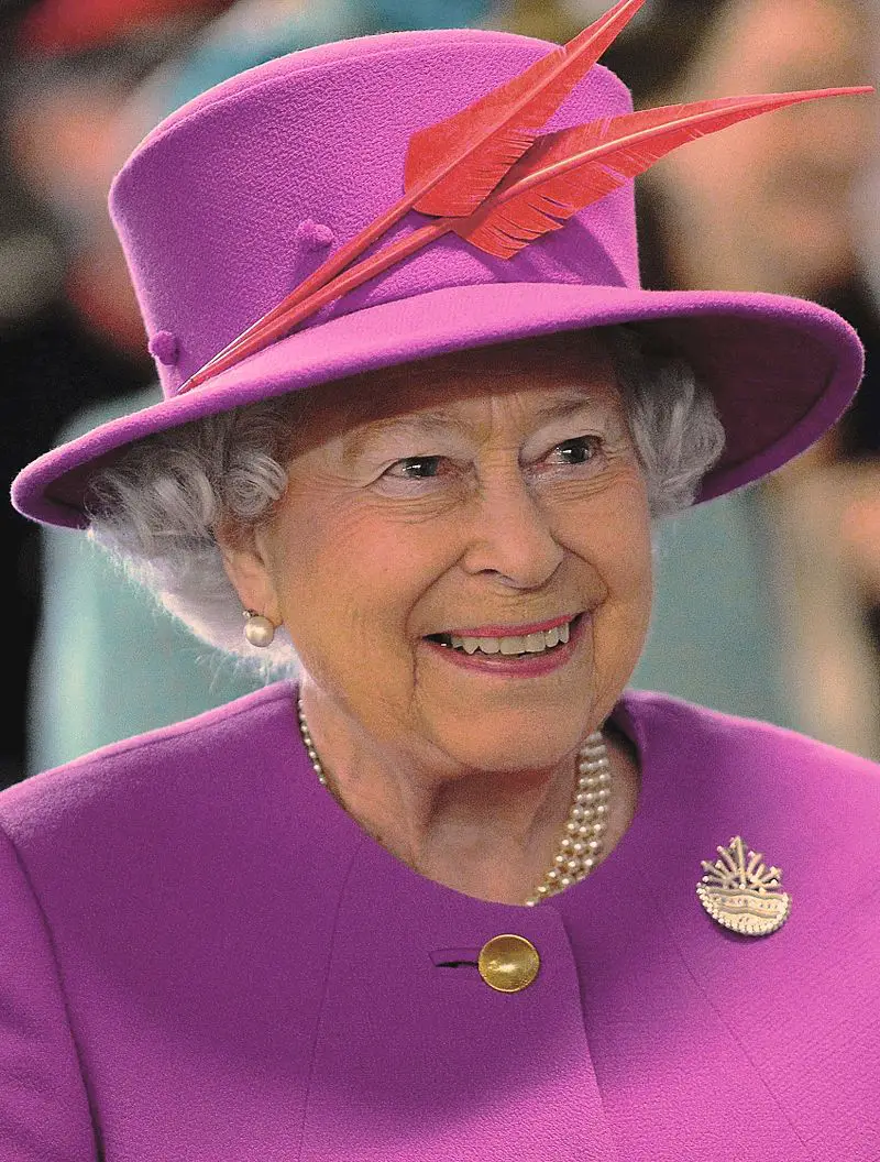 photo of Queen Elizabeth in purple hat with red leaves and a purple dress