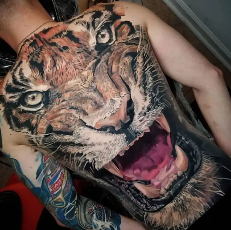 realistic large face of an angry Tiger Tattoo on the back of a man