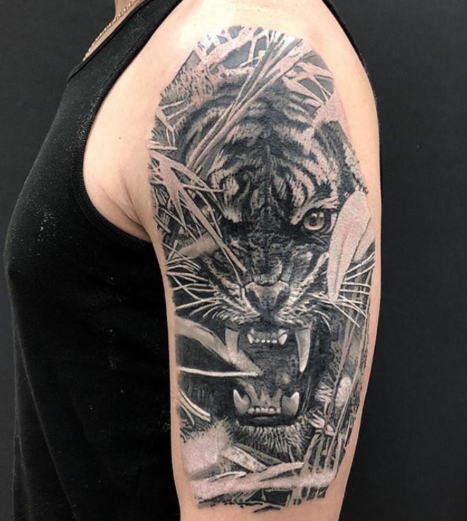 A black and gray angry face of a Tiger Tattoo on the shoulder