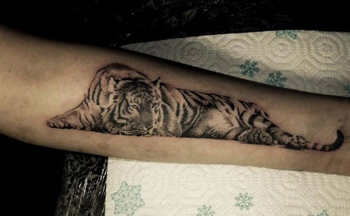 Black and gray lying down tattoo on the forearm