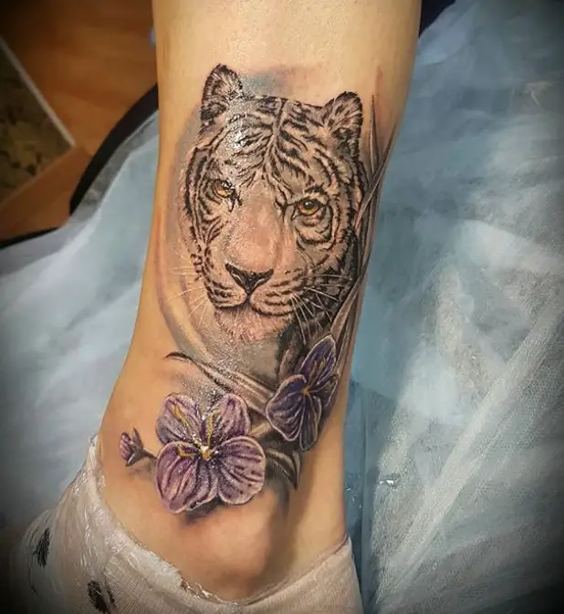A realistic Tiger Tattoo with purple flowers tattoo on the leg