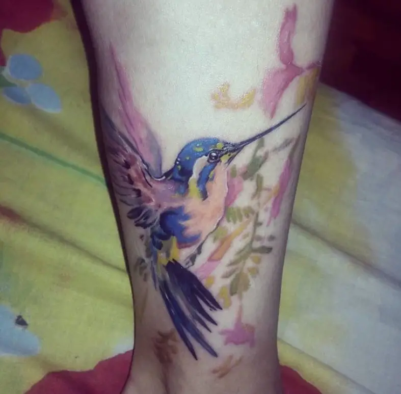 watercolor hummingbird feeding on flowers tattoo on the leg