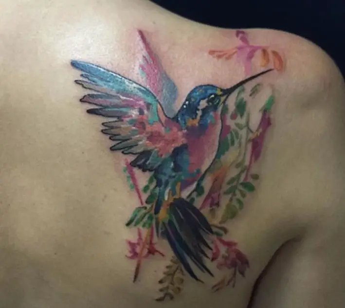colorful watercolor hummingbird on flowers tattoo on the back