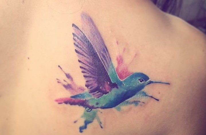 purple, blue, and green watercolor hummingbird tattoo on the shoulder