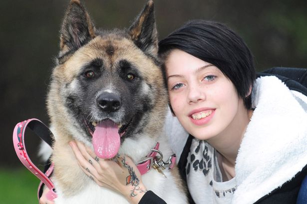 Aysha Perry smiling beside its Akita Inus dog