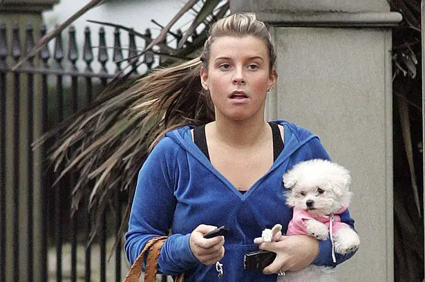 Coleen Rooney walking in the street while carrying her Bichon Frise