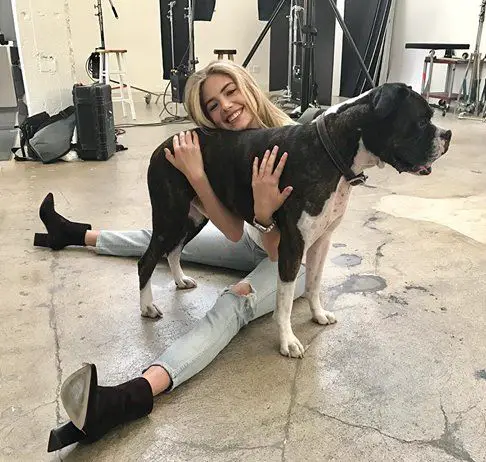Kate Upton sitting on the floor hugging the body of her Boxer Dog