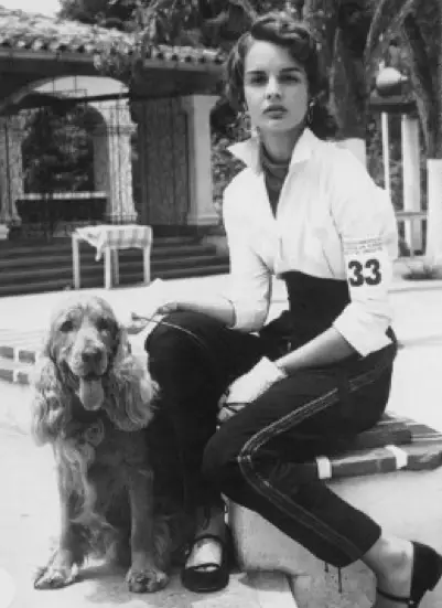 Carolina Herrera sitting on the bench with her Cocker Spaniel siting on the floor