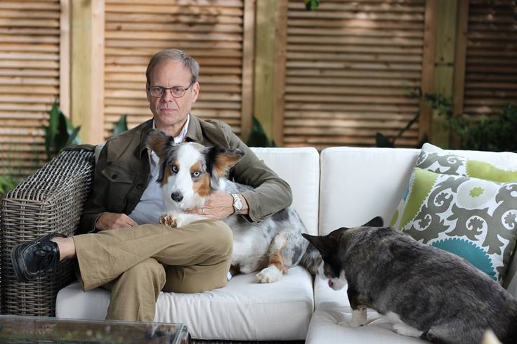 Alton Brown sitting on the couch with his arm around his Corgi